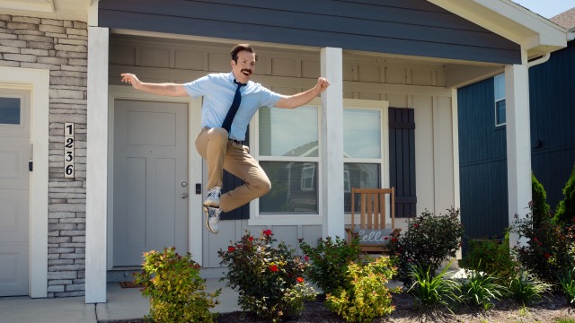 Jason Sudeki as Ted Lasso jumping off the porch happily