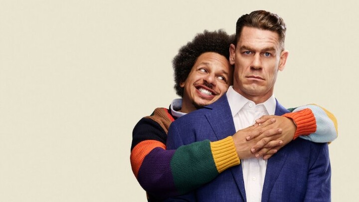 Eric Andre hugging a stern looking John Cena from behind