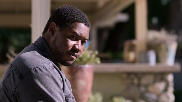 alt="Luke Tennie as Sean sitting outside in the sun in Shrinking"