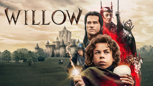 alt="Val Kilmer and Warwick Davis in Willow, a 1988 fantasy film, standing before a castle with mystical and dark characters behind them"