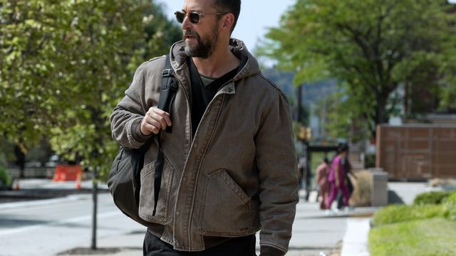 alt="Dr. Michael “Robby” Robinavitch walks outdoors with a shoulder bag, wearing a jacket and sunglasses."