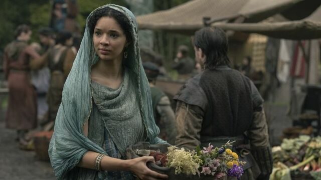 alt="Tanzyn Crawford as Tanselle holding flowers in a market dressed in a blue head dress in A Knight of the Seven Kingdoms."